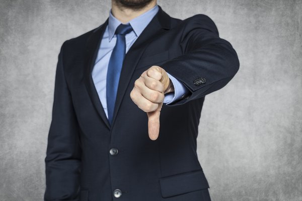 A person wearing a suit and giving a thumbs down.