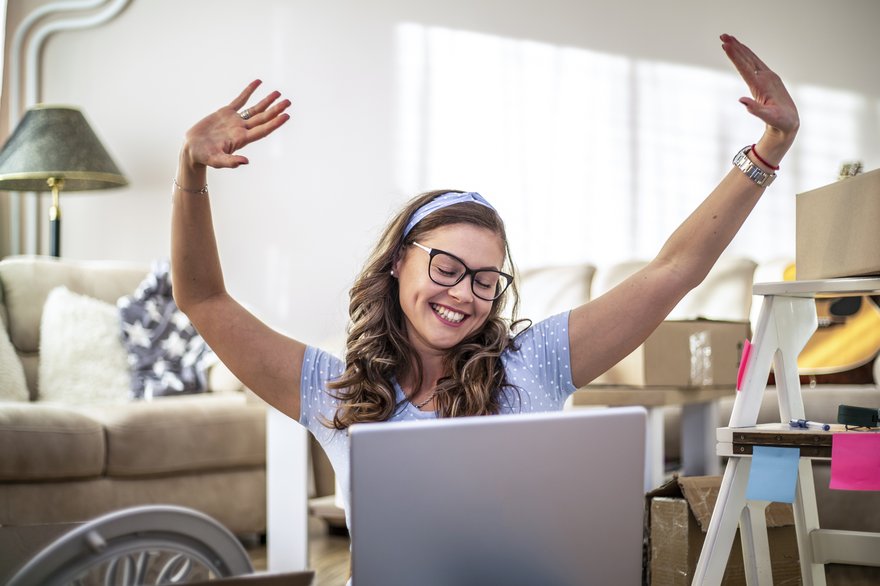 Person in front of computer is excited and smiling with hands in air.