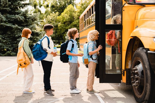 Children waiting in line to board a school bus.