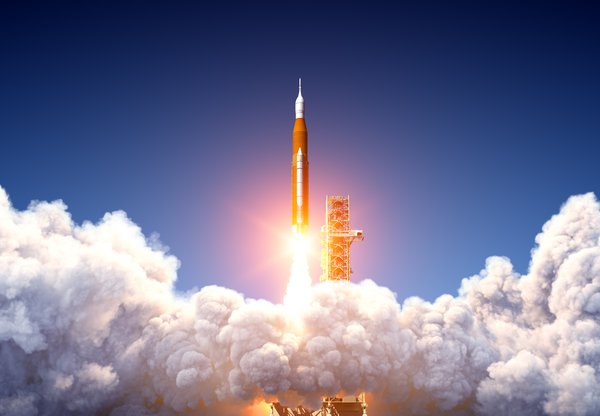 A rocket shooting straight up into the sky above the clouds.