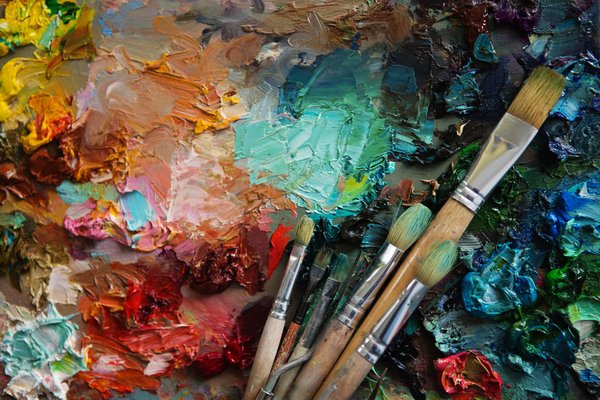 Paint brushes lie atop a painting in progress.